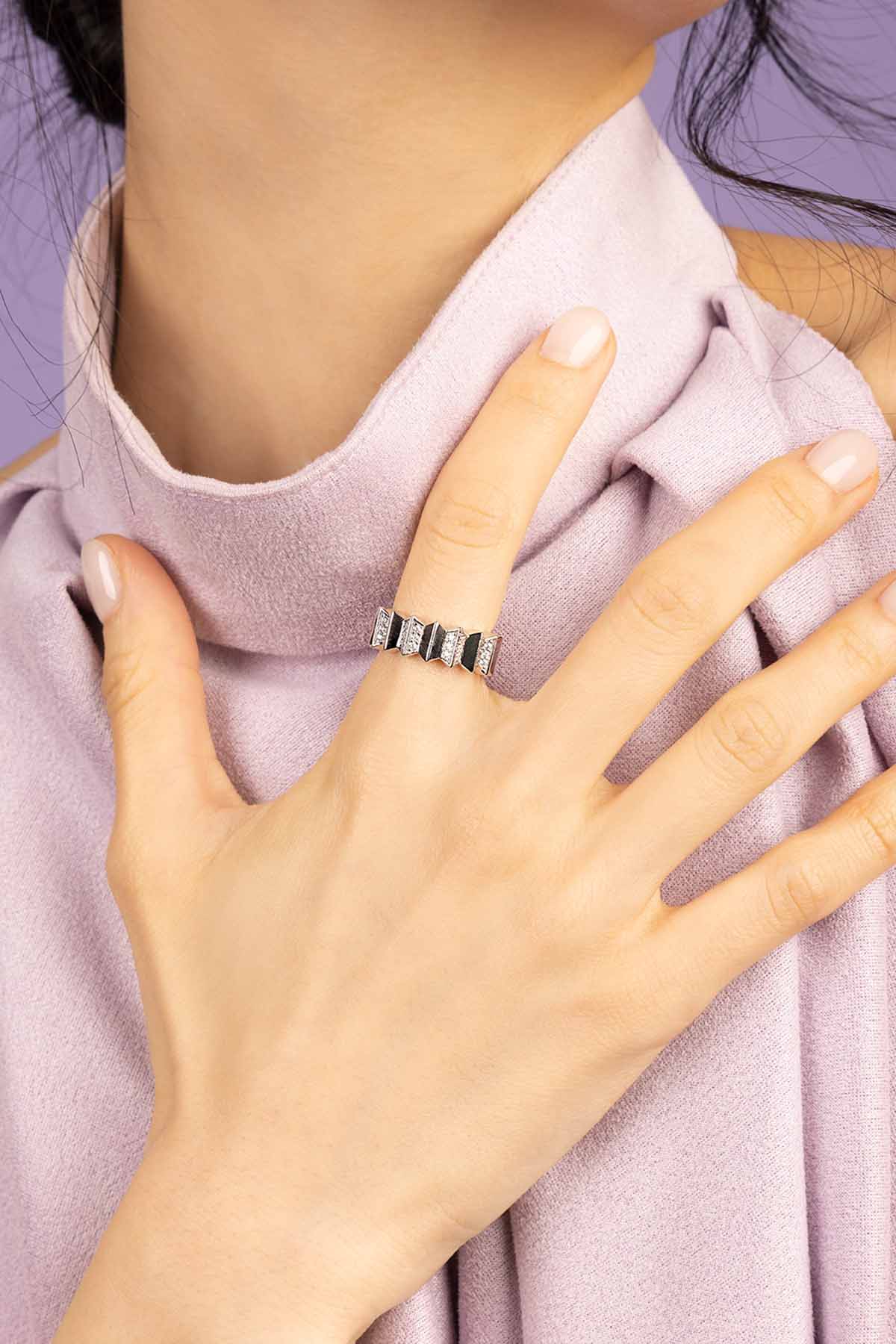 Close-up of a hand wearing a ring on a light purple fabric background