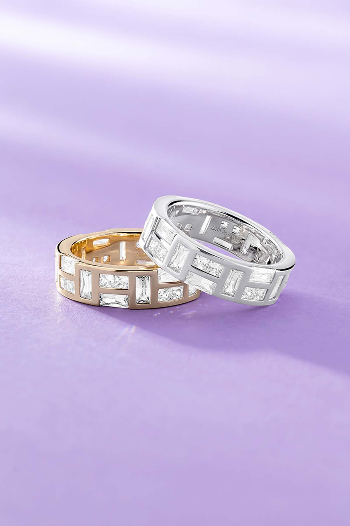 Two APM MONACO ice rings on a purple background, one is yellow god one is silver