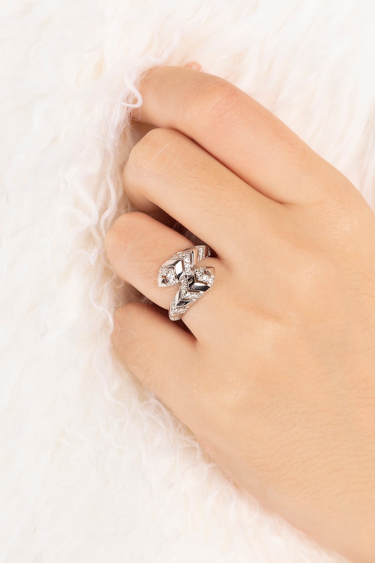 Hand wearing a silver ring with zirconia stones on a white background