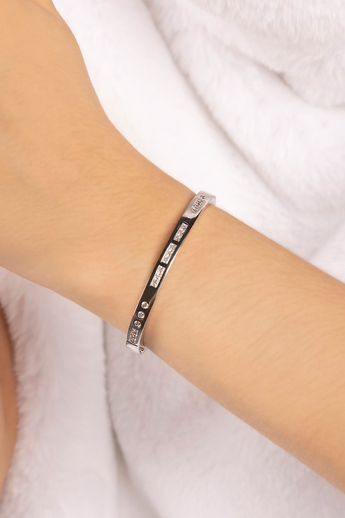 Silver bracelet on a person's wrist against a white background