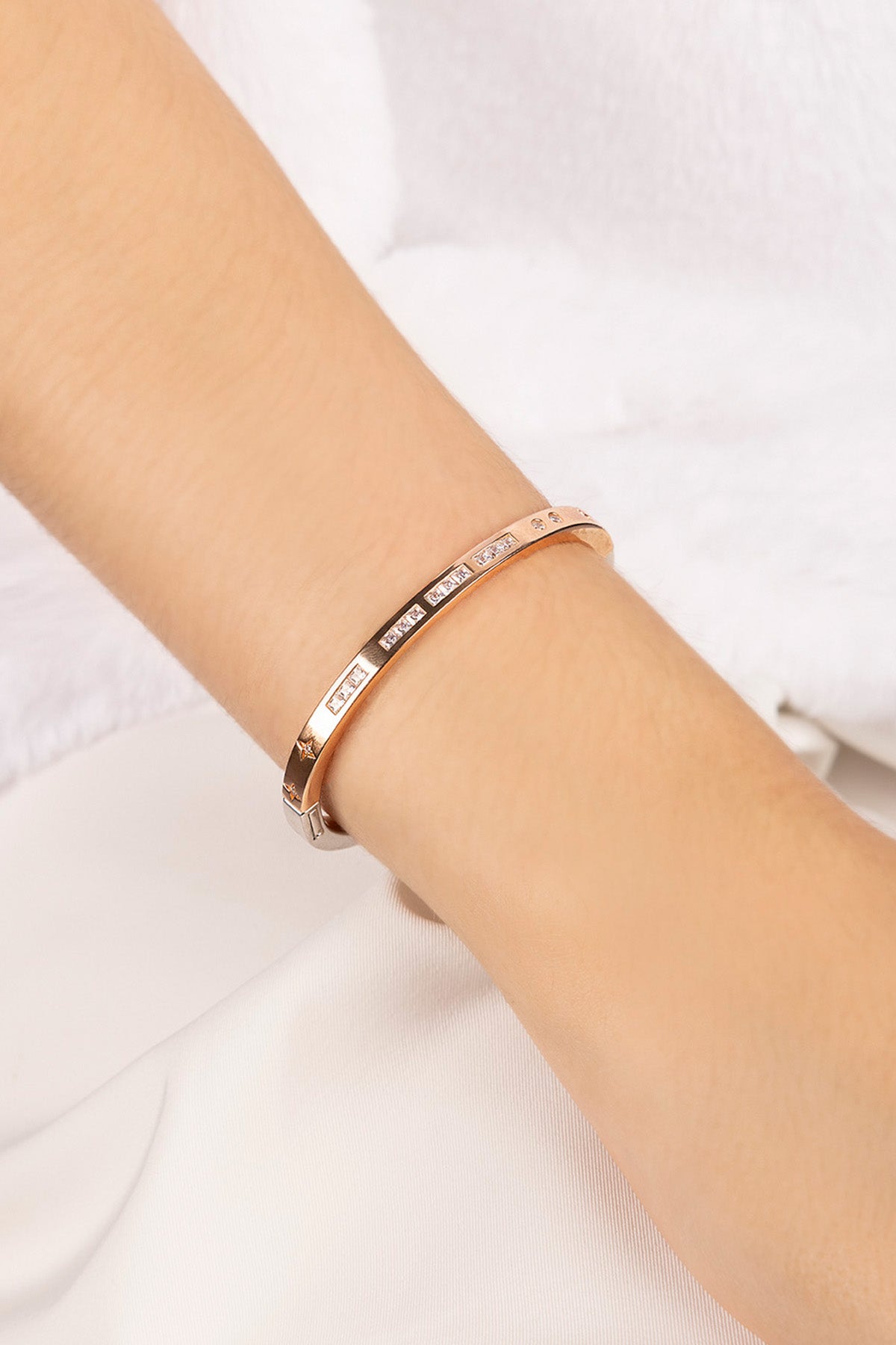 Rose gold bracelet on a person's wrist against a white background