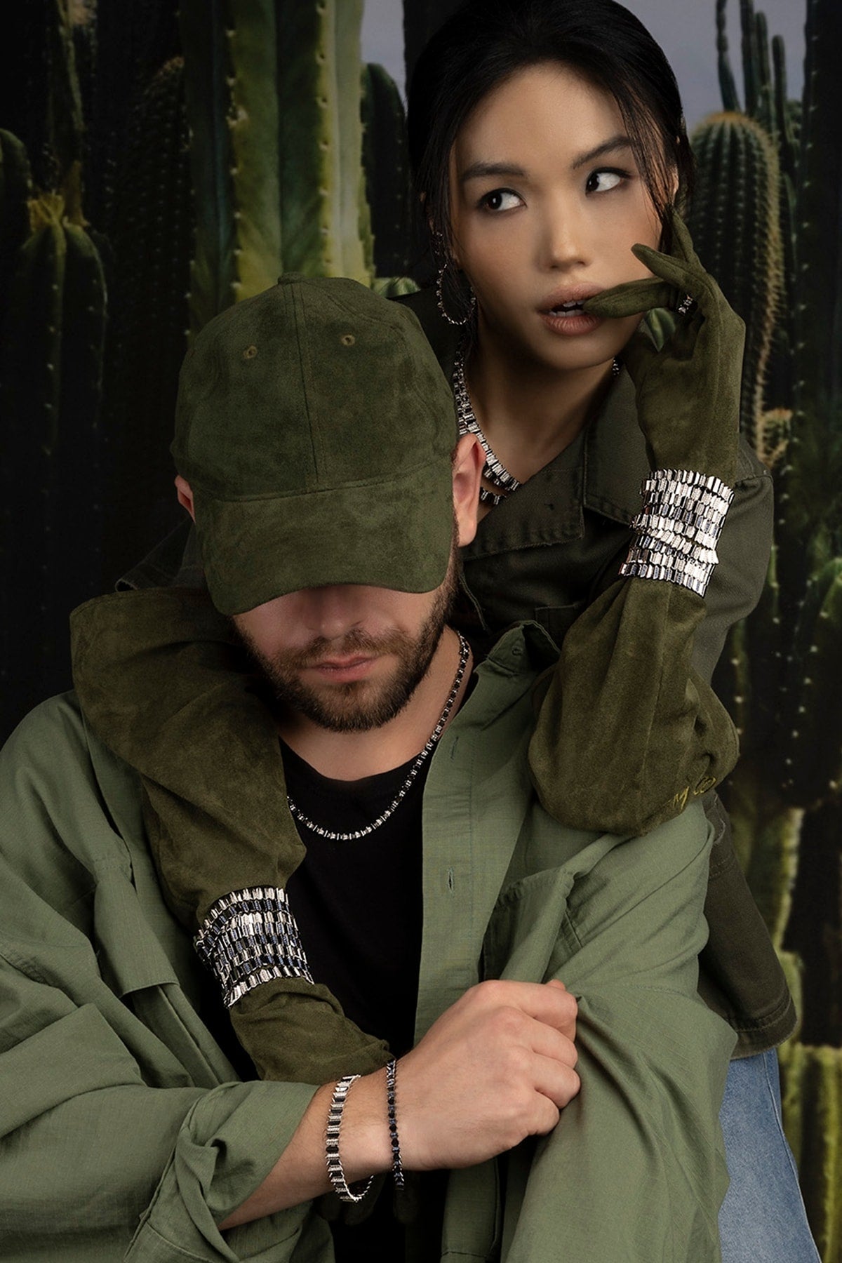 Two models in green jackets with jewelry in cacti background