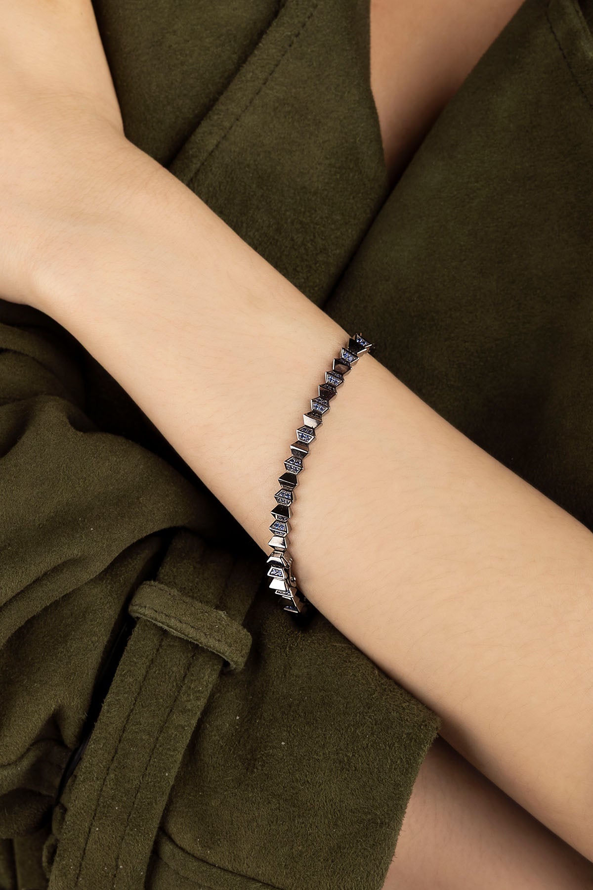 APM Monaco Up and Down Bracelet in dark grey on a wrist against a green background