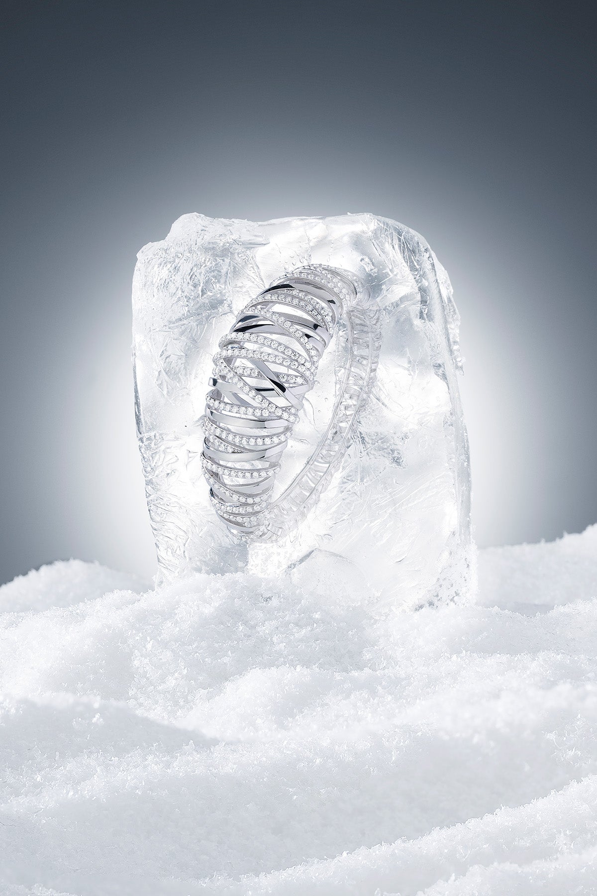 APM MONACO enlace silver bangle encased in ice on a snowy background