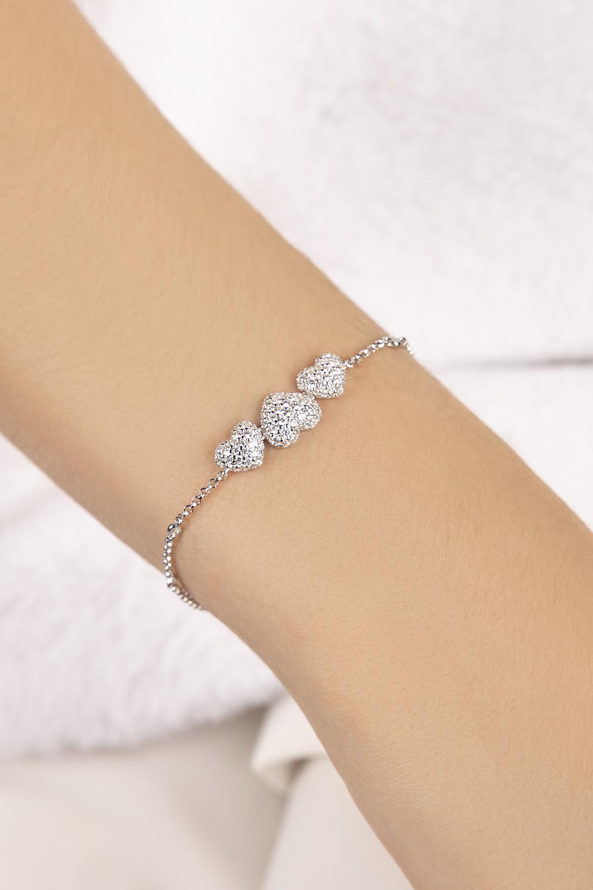 Heart-shaped adjustable bracelet in silver on model's wrist from APM MONACO
