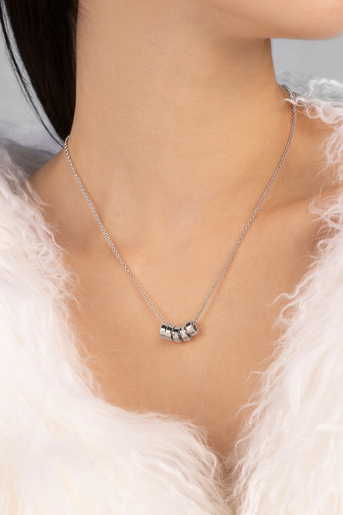 Necklace with a subtle design worn by a person against a neutral background