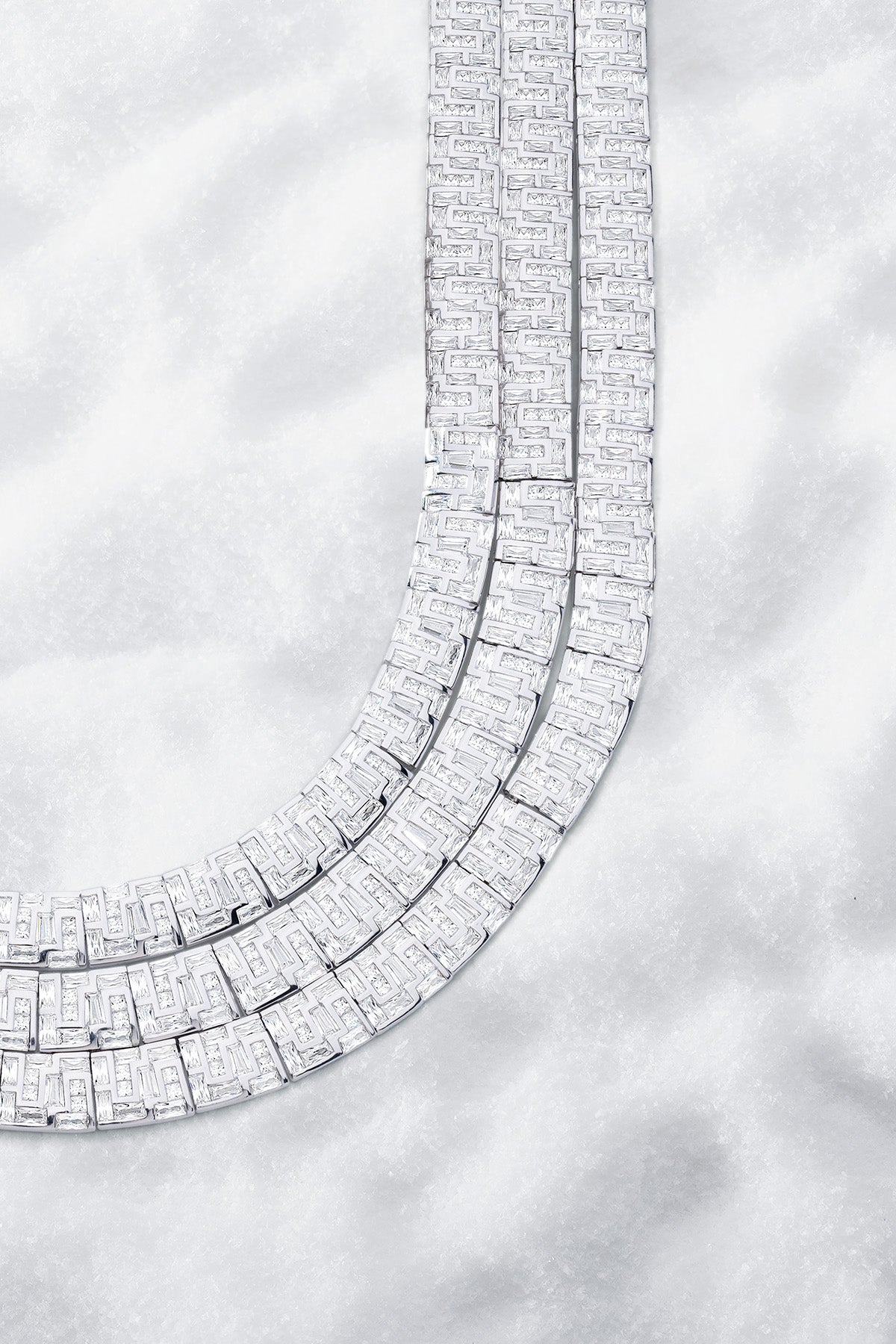 APM MONACO labyrinth necklace in silver on a light gray snowy background