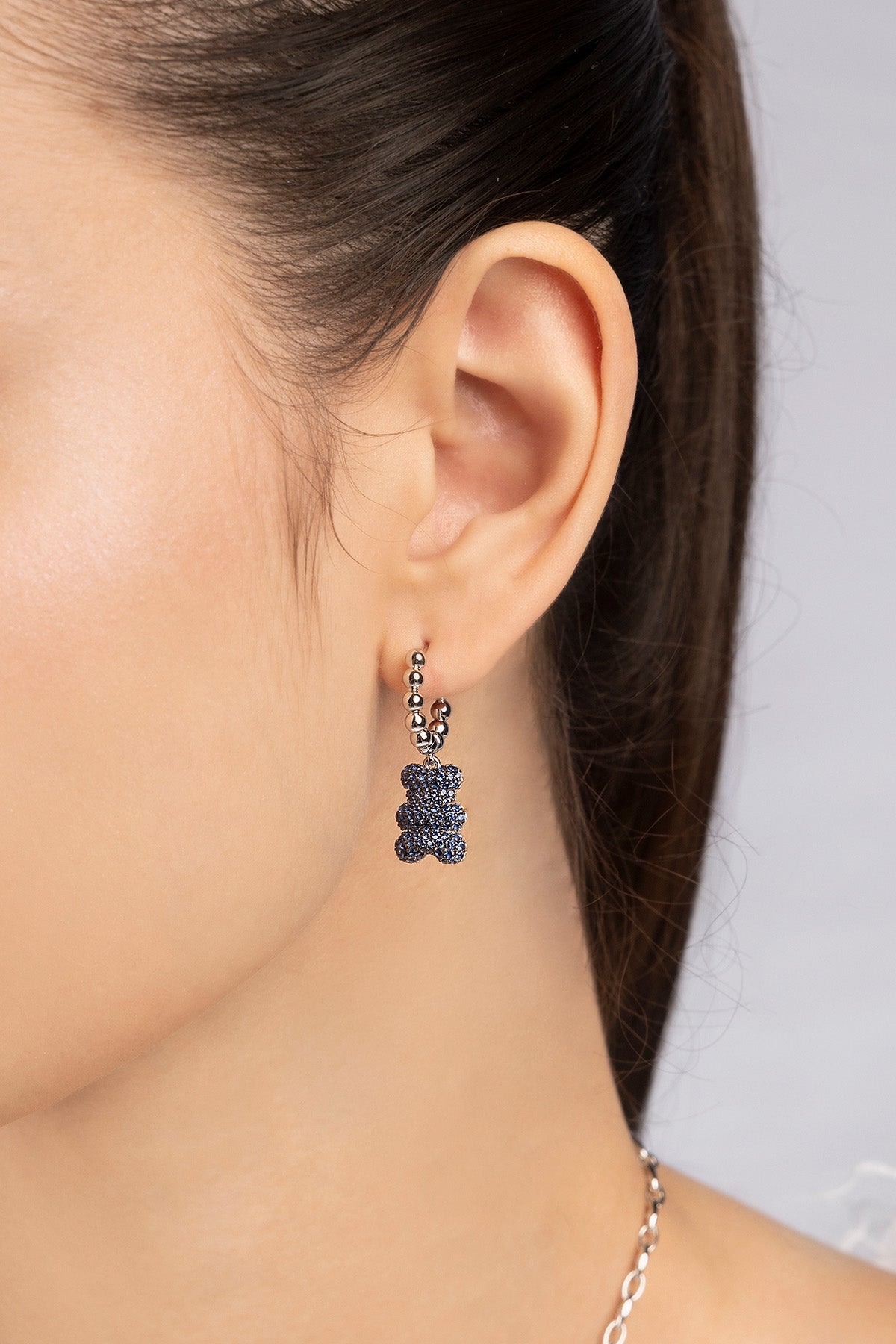Close-up of an ear wearing a silver earring  with baby yummy bear hoop design worn on model 