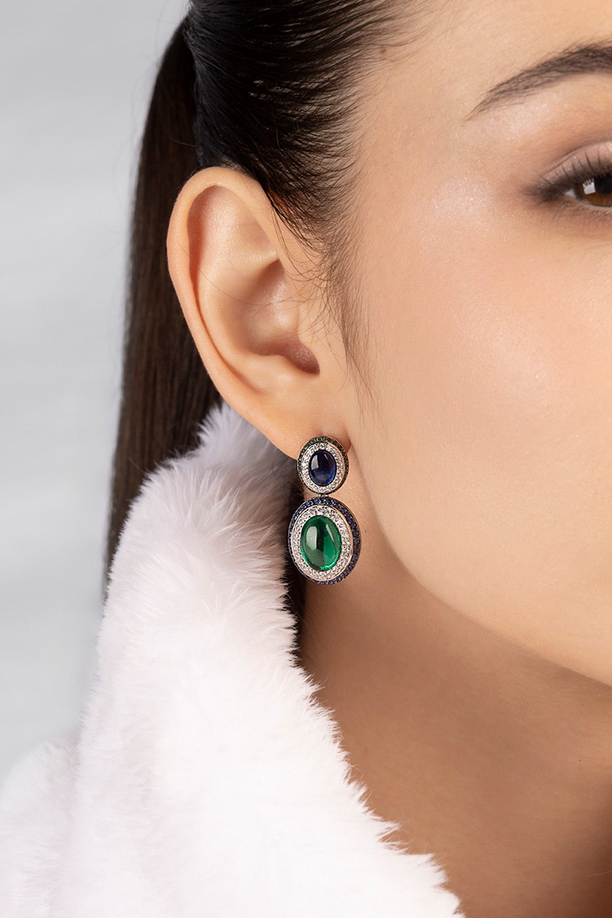 Close-up of a woman wearing a pair of earrings with a white fur collar.