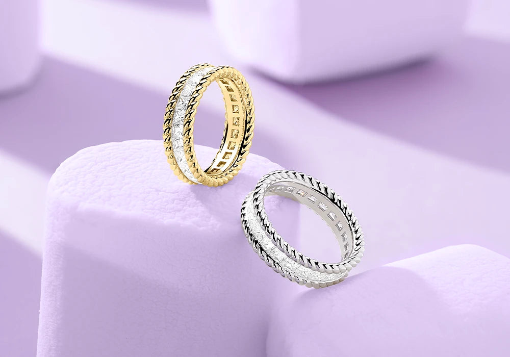 Two APM MONACO torsade rings in yellow gold and silver on light purple marshmallows