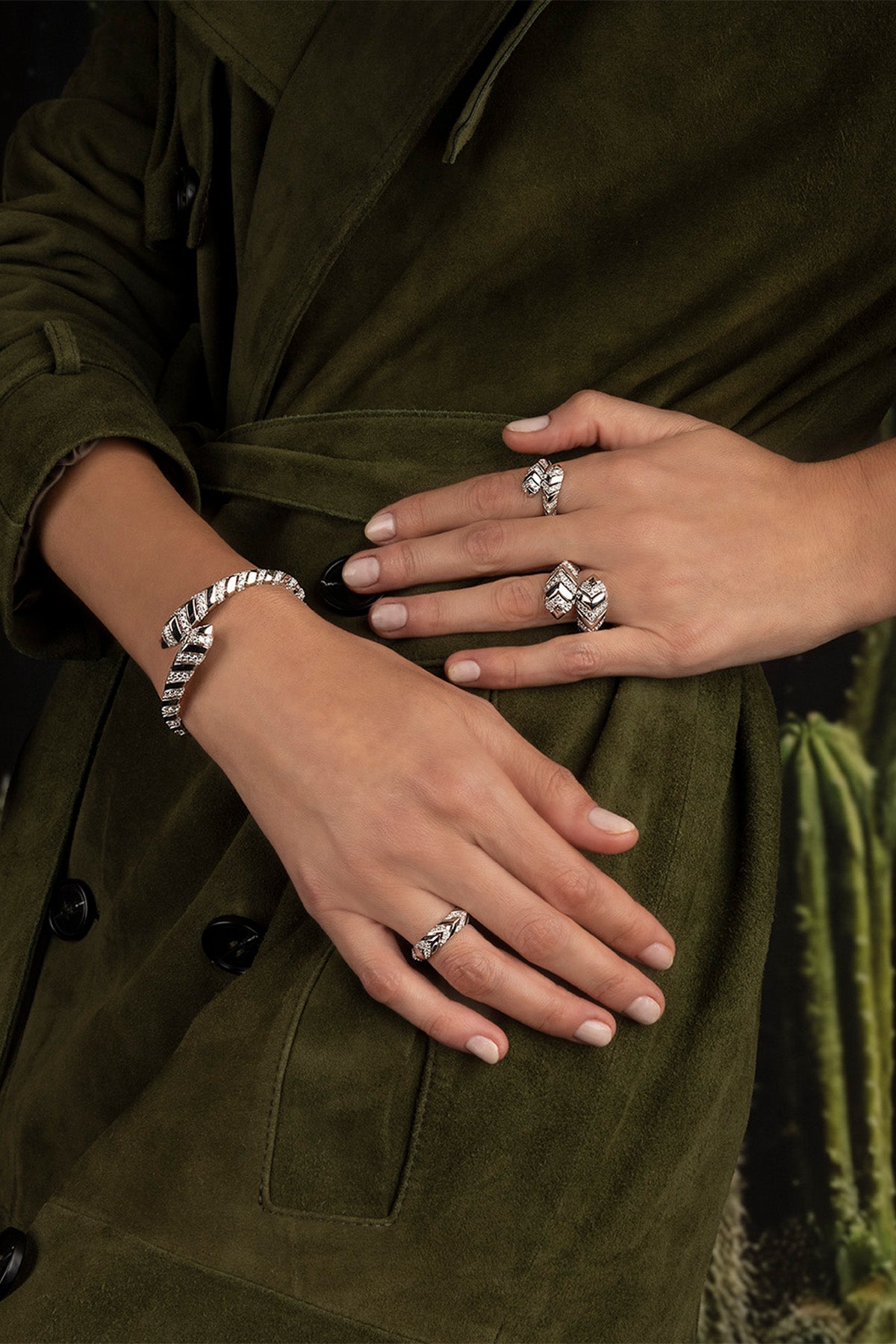 Close-up of hands wearing multiple rings on a green fabric background