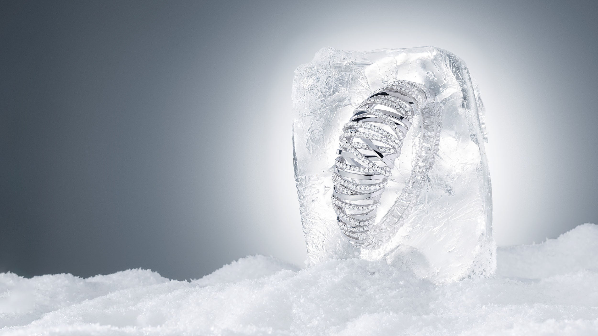 APM MONACO Hiver Enlace ring in silver encased in ice on a snowy background