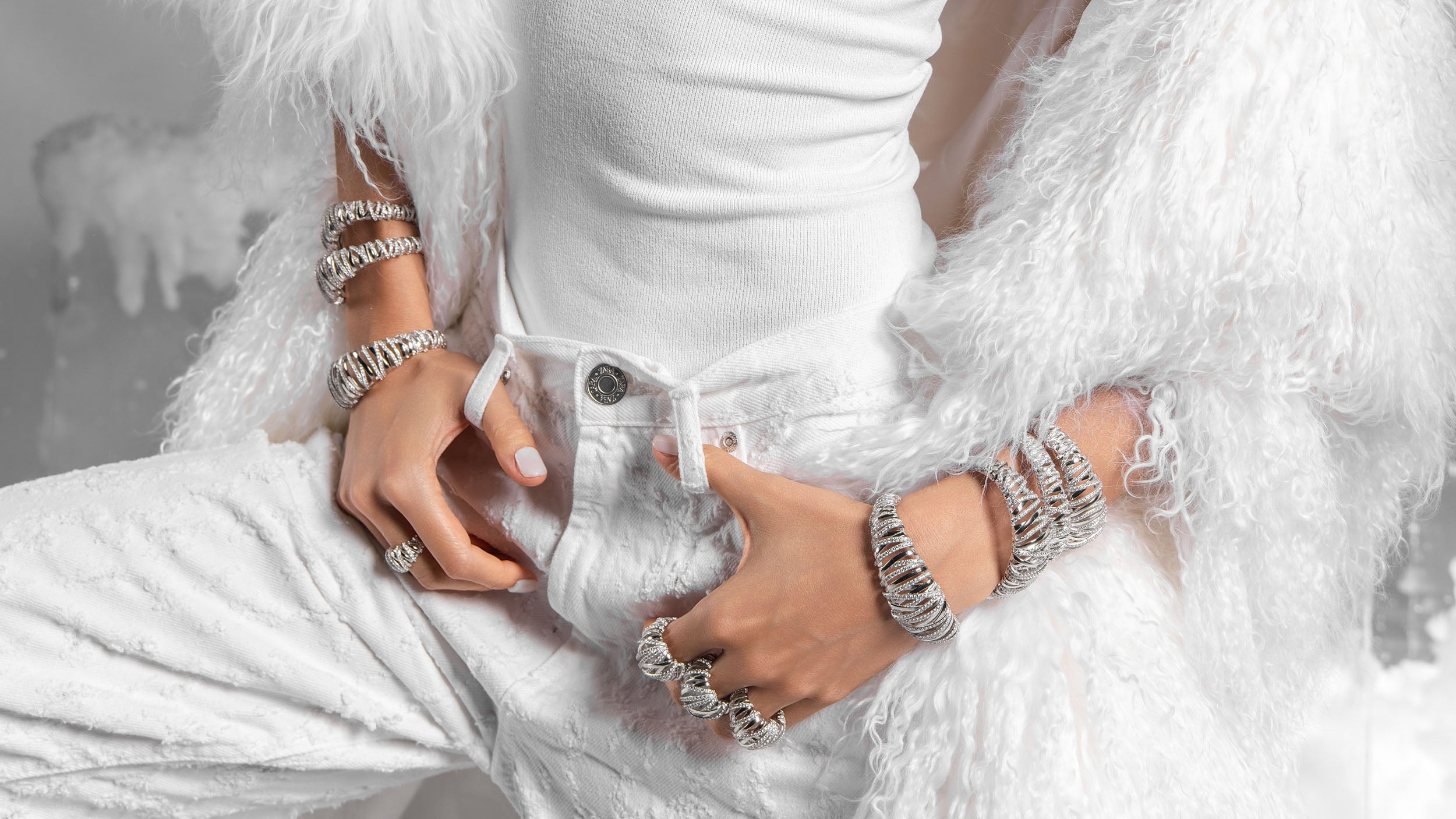 Person in a white dress with feathered sleeves wearing APM MONACO enlace jewel set in silver