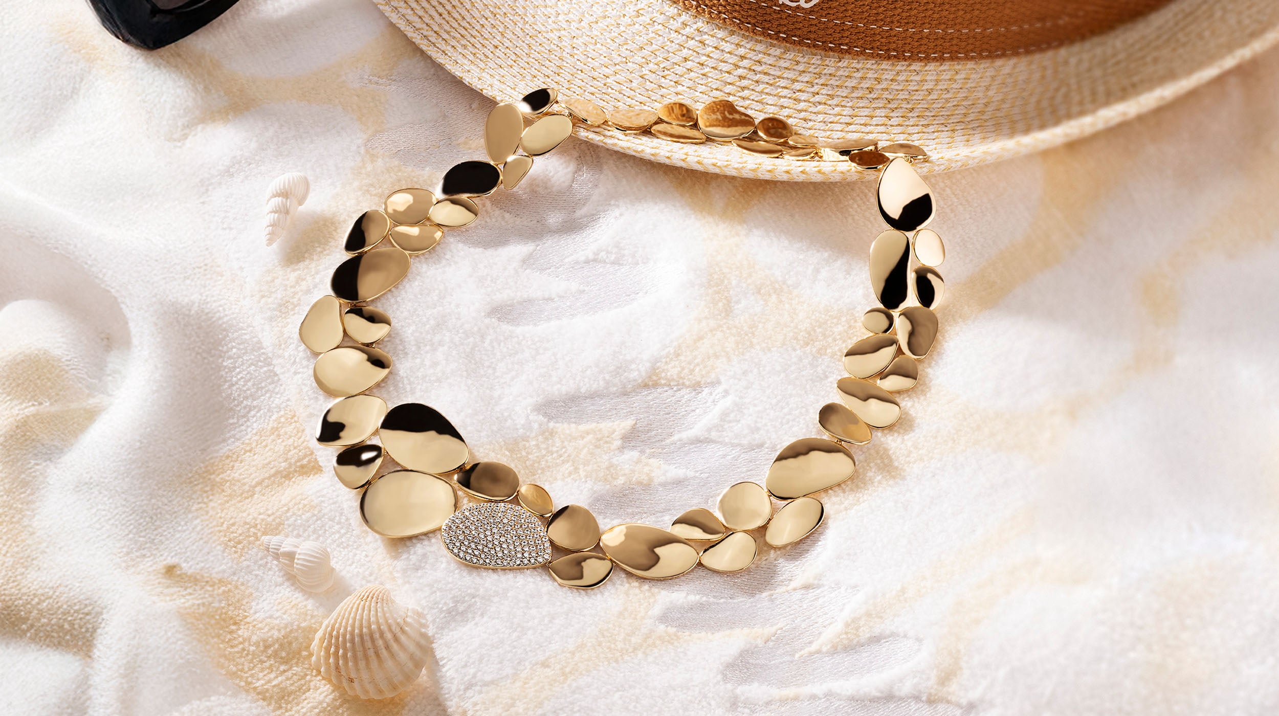APM MONACO yellow gold necklace from soleil collection on a sandy background