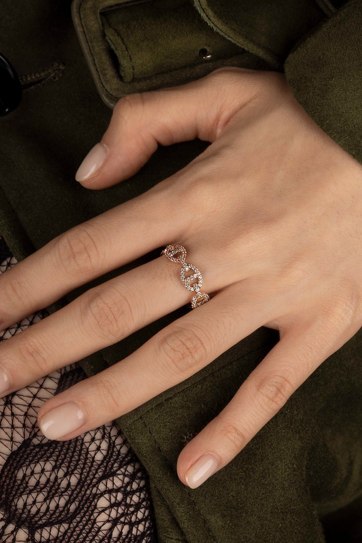 Close-up of a hand wearing a ring with a green dark background