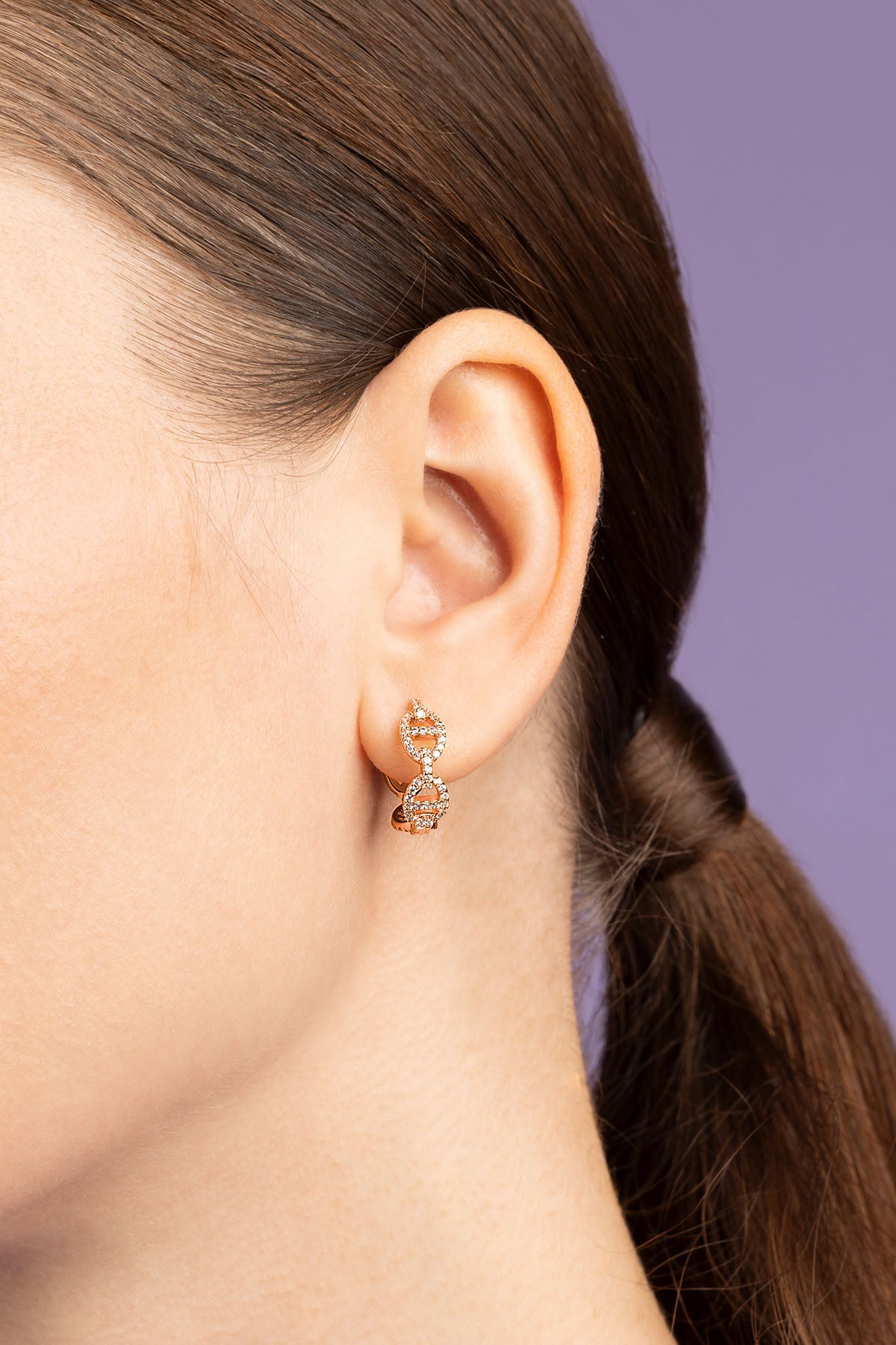 Close-up of an ear wearing a delicate earring with a dark background